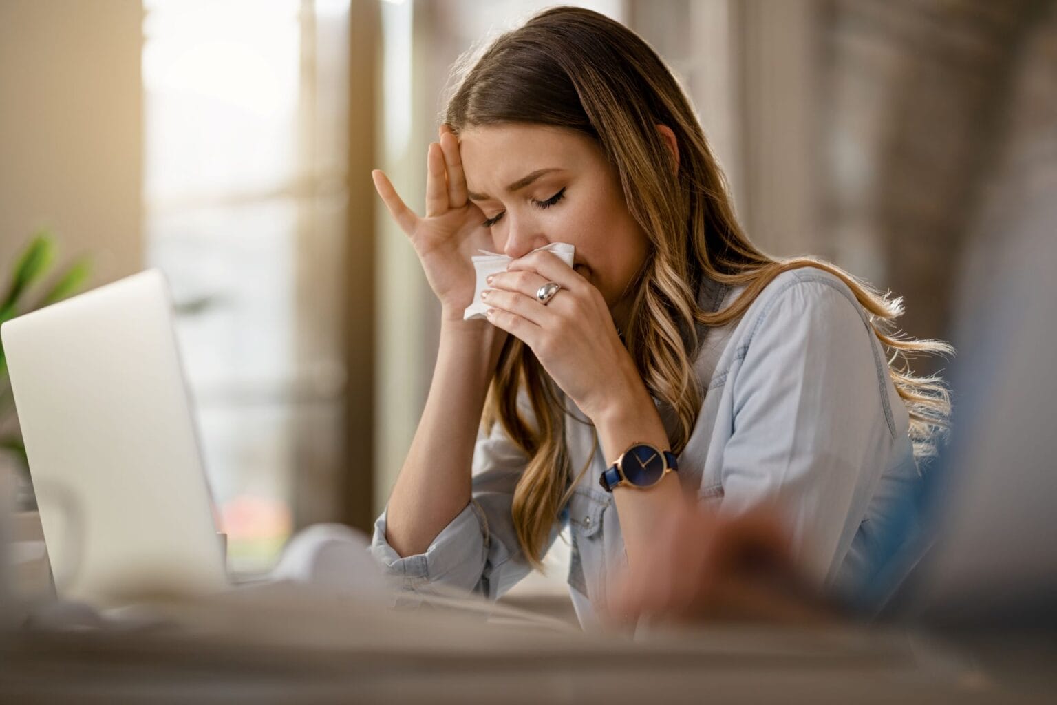 Woman with allergies sneezes while at work